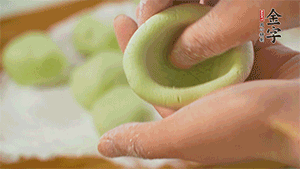 將均分的艾草面團(tuán)搓成圓，挖一個(gè)窩，放入餡心，再搓成圓。