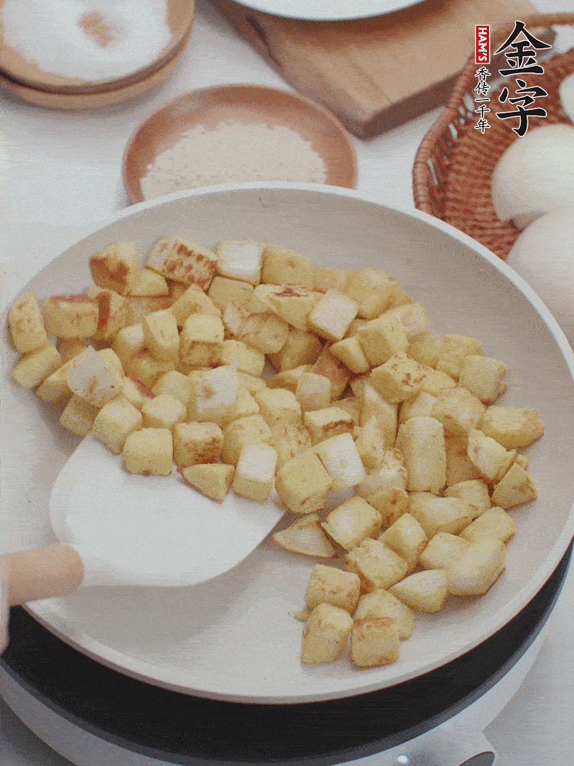 起鍋熱油，倒入饅頭丁，小火煎至蛋液凝固定型再翻面，饅頭丁部煎至金黃時(shí)盛起待用。